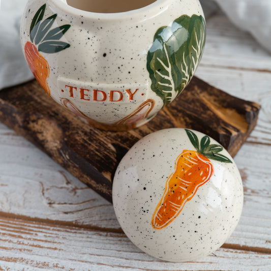 Top view of the heart-shaped memorial vessel showing the hand-painted carrots, cabbage, and ceramic lid.