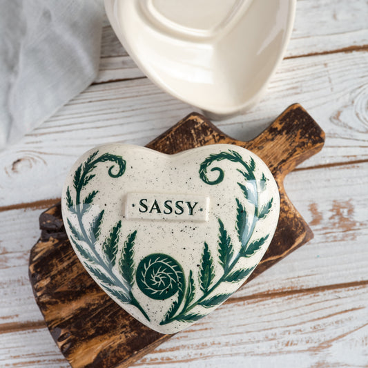 Top view of the ceramic heart urn, showing the detailed green fern fronds and botanical illustration.