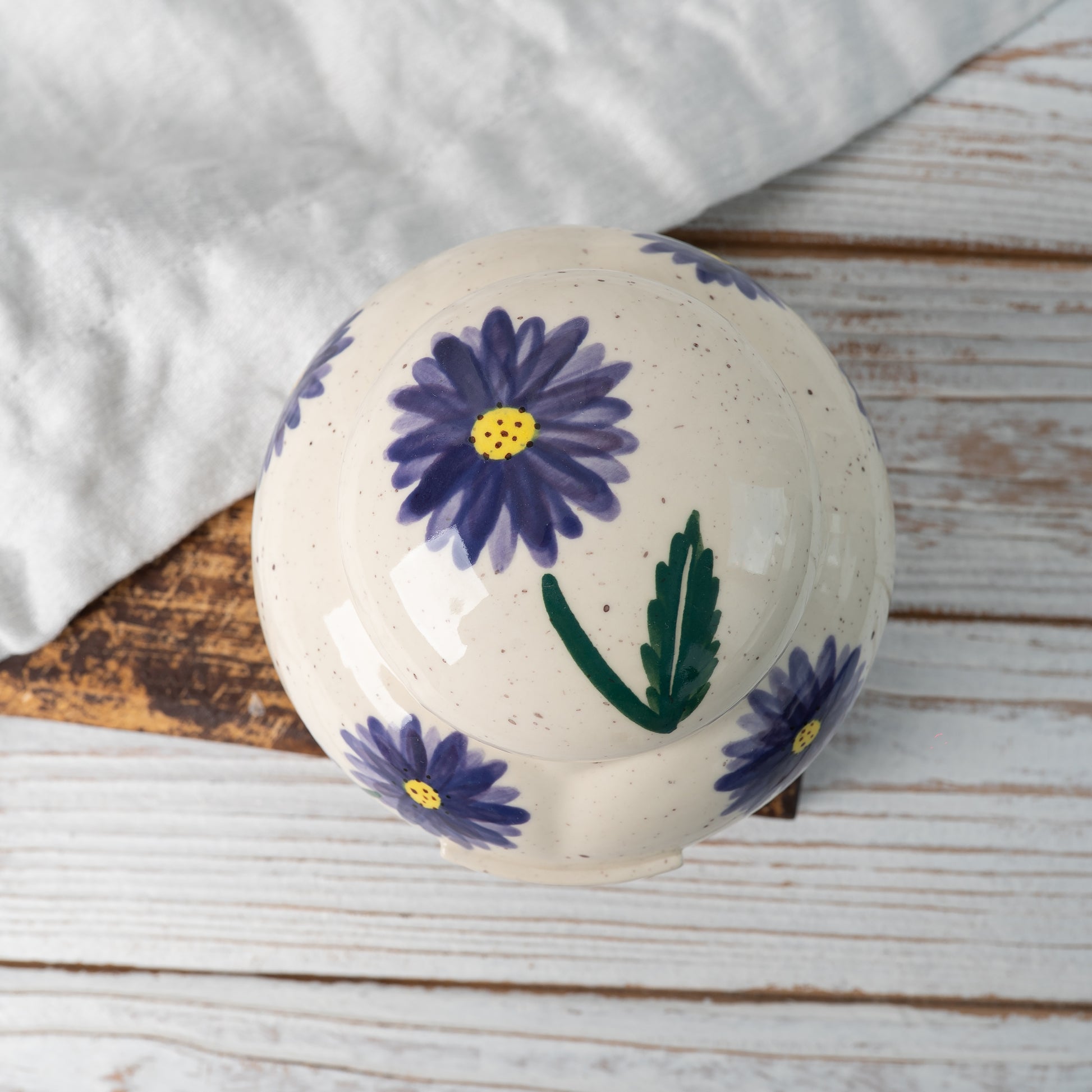 Top-down view of hand-painted ceramic lid with aster floral design for heart keepsake urn