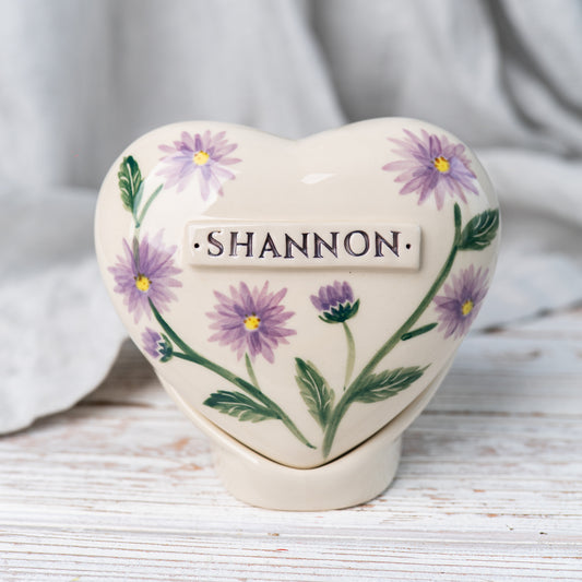 Hand-painted heart-shaped ceramic urn with aster flowers and a matching stand for human or pet ashes.