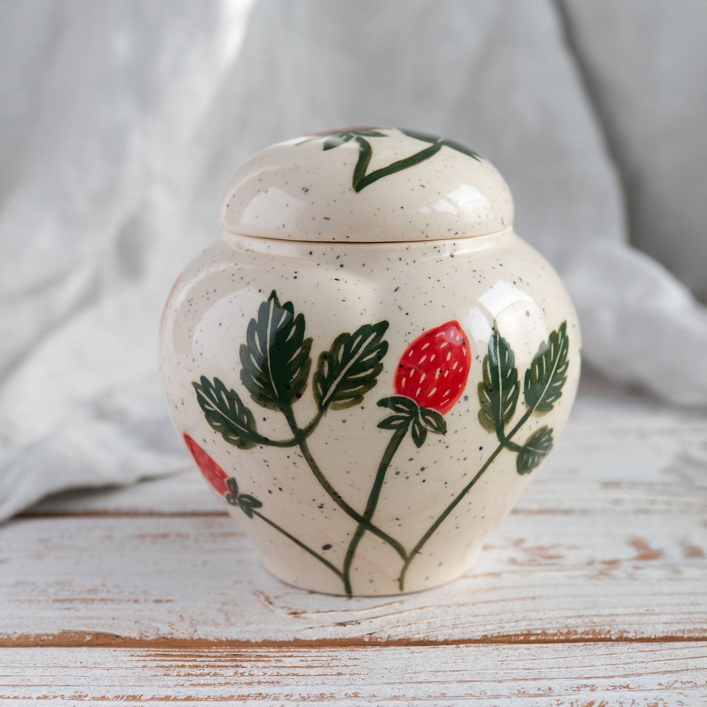 Back side view of the strawberry and painted bunny ears ceramic rabbit urn, showing the pot-style silhouette.