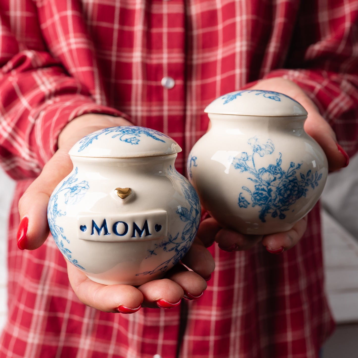 A person gently holding two blue flower print keepsakes in their hands