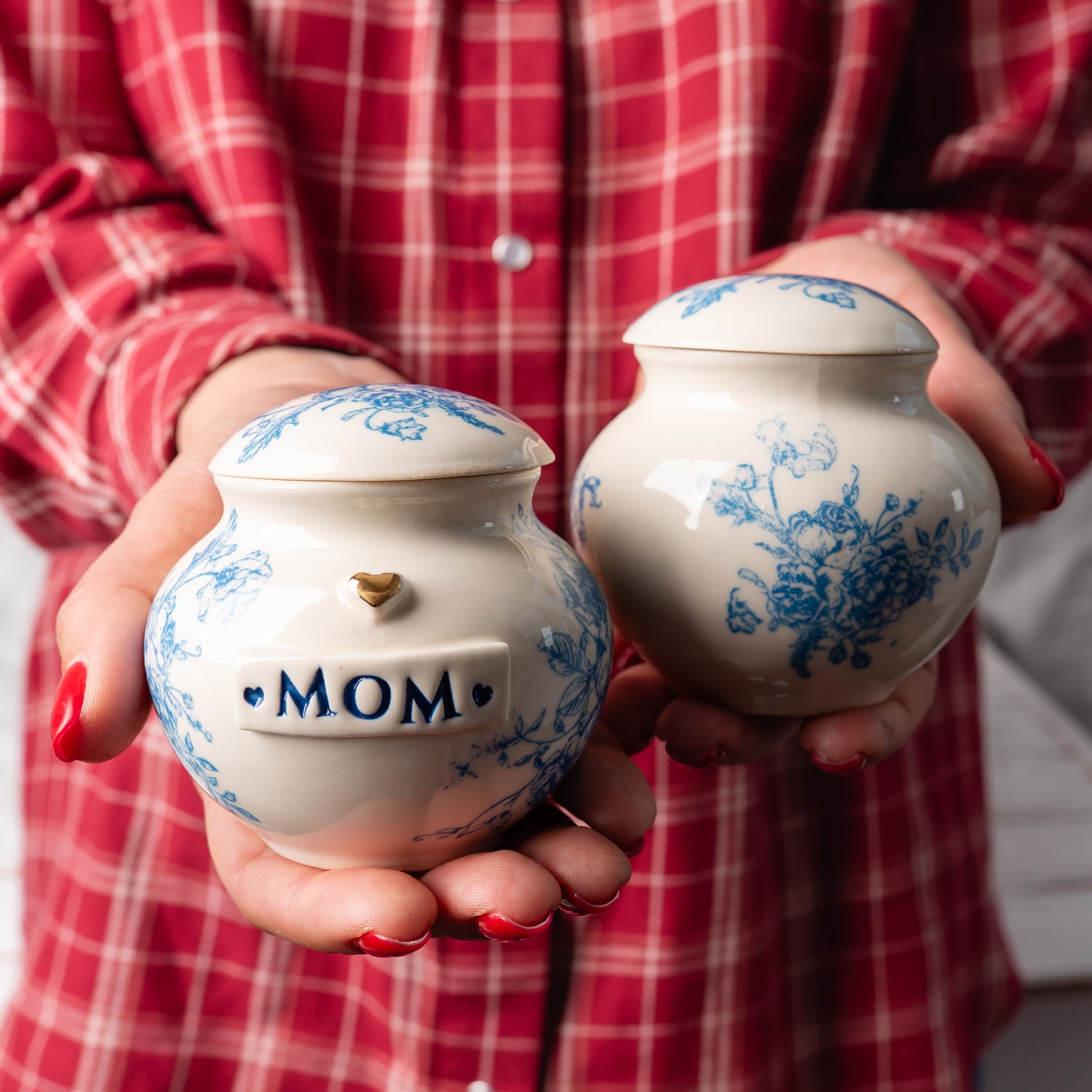 A person gently holding two blue flower print keepsakes in their hands