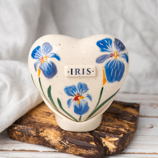 Hand-painted heart-shaped ceramic urn with blue irises and a matching stand for human or pet ashes.