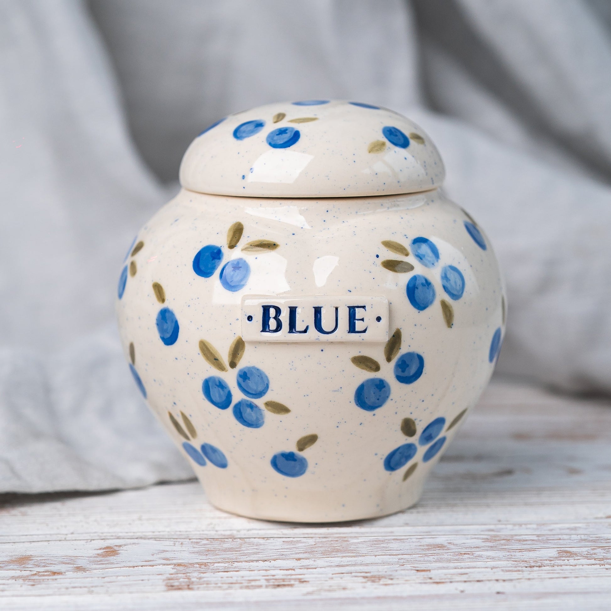 Hand-painted pot-style heart-shaped ceramic pet urn with blueberries for ashes.