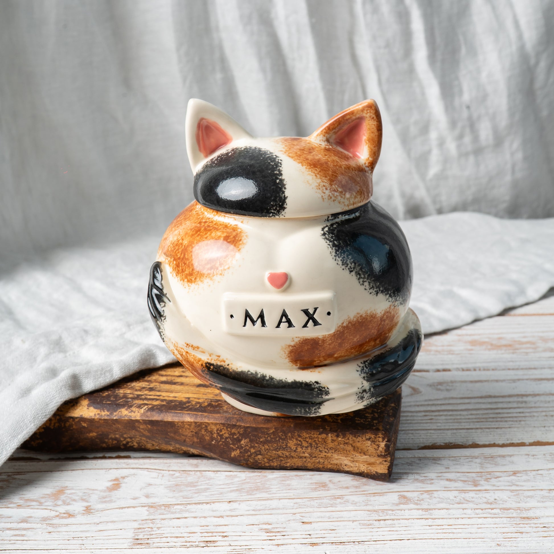 Calico cat heart-shaped ceramic urn for ashes with sculpted cat ears and tail front view