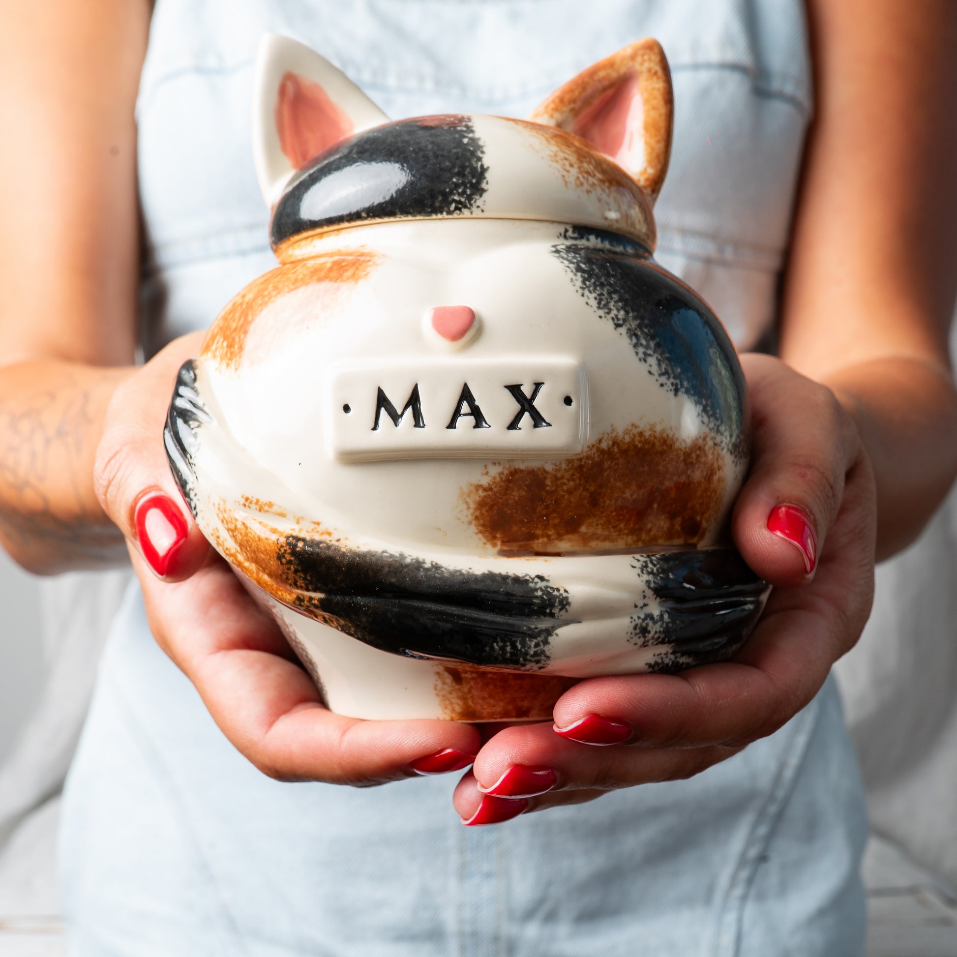 Small custom heart ceramic calico cat keepsake urn held gently in hands for scale