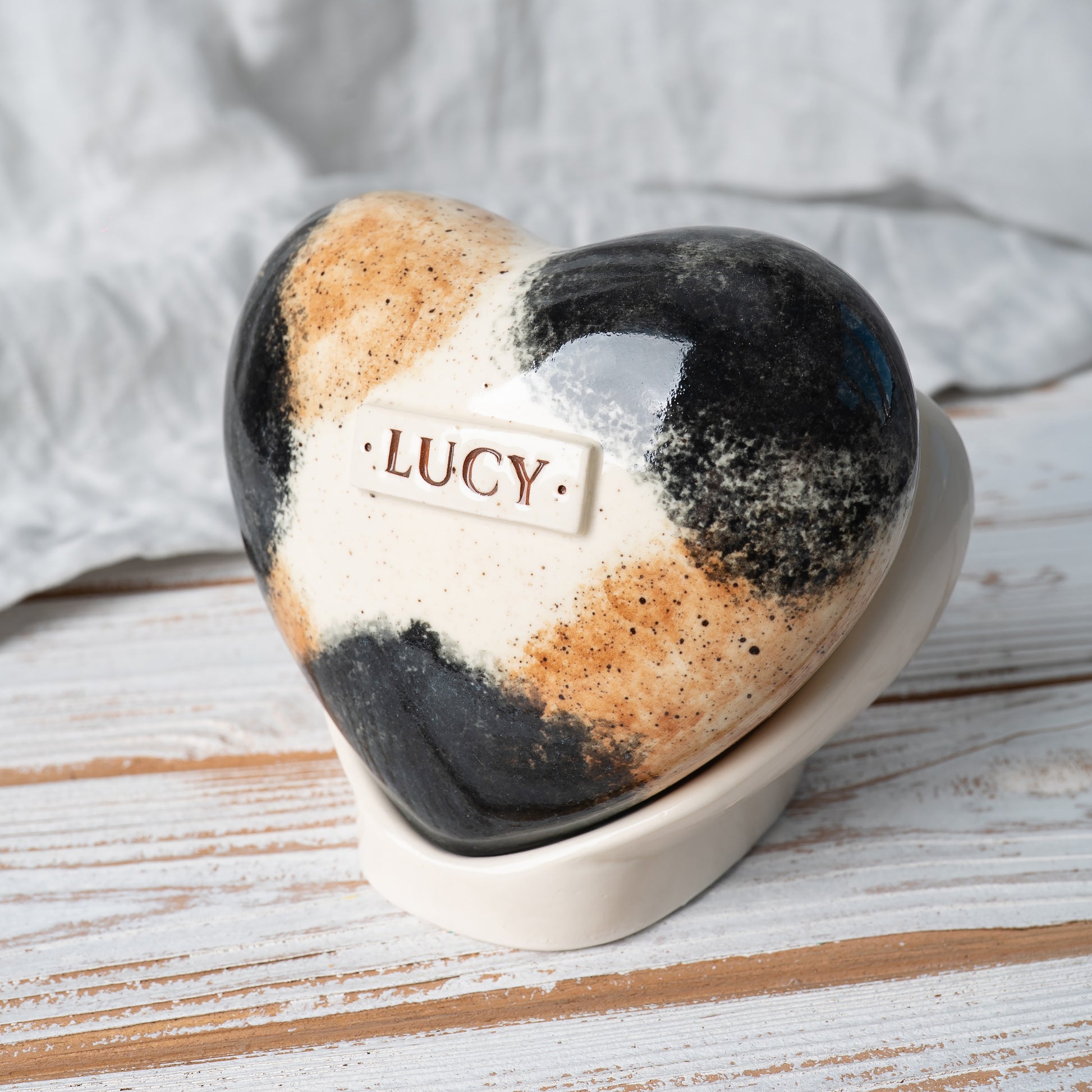 Side profile of a ceramic calico cat memorial urn, highlighting the elegant heart shape and smooth glazed finish