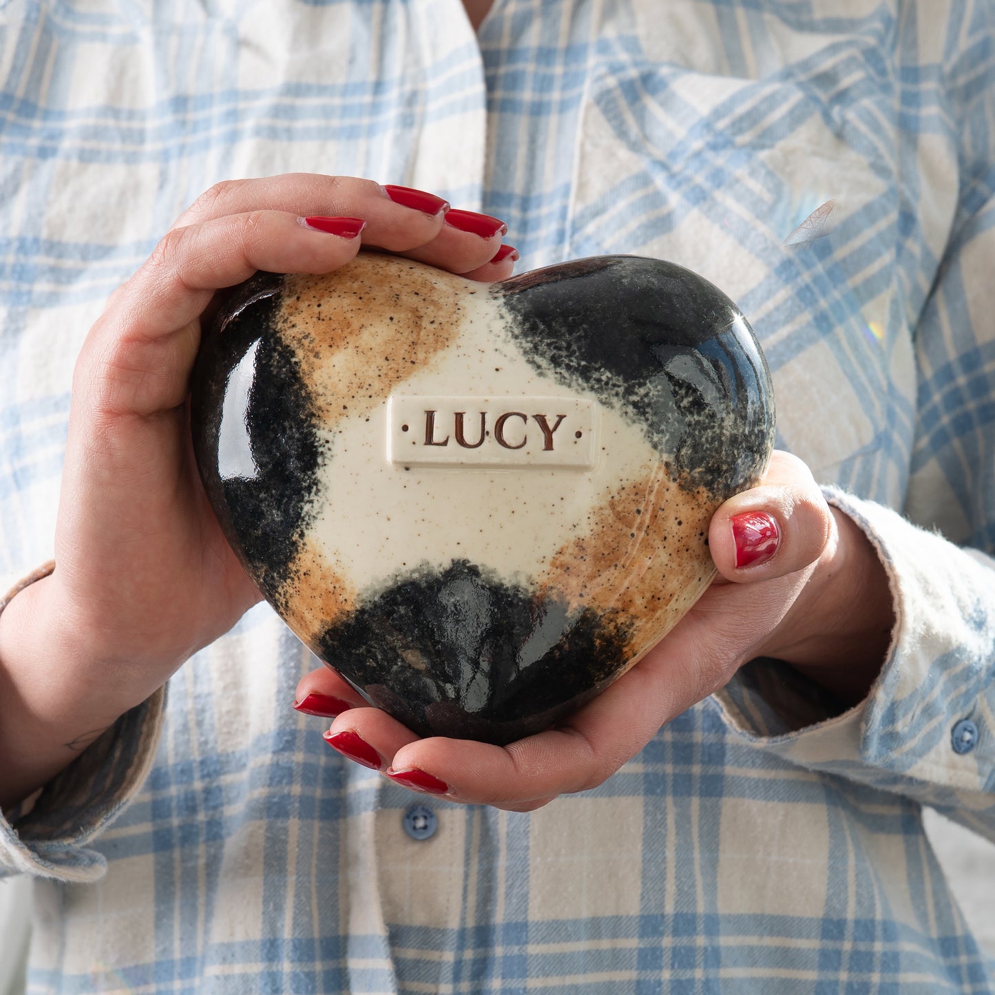 Small calico cat keepsake urn held in hands to demonstrate size and artisan detail by Mira Ceramics.