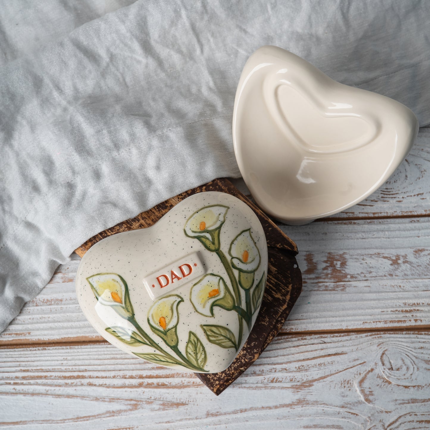 Detailed top view of the heart-shaped urn showing the artisan hand-painted white calla lily design and smooth glazed finish.