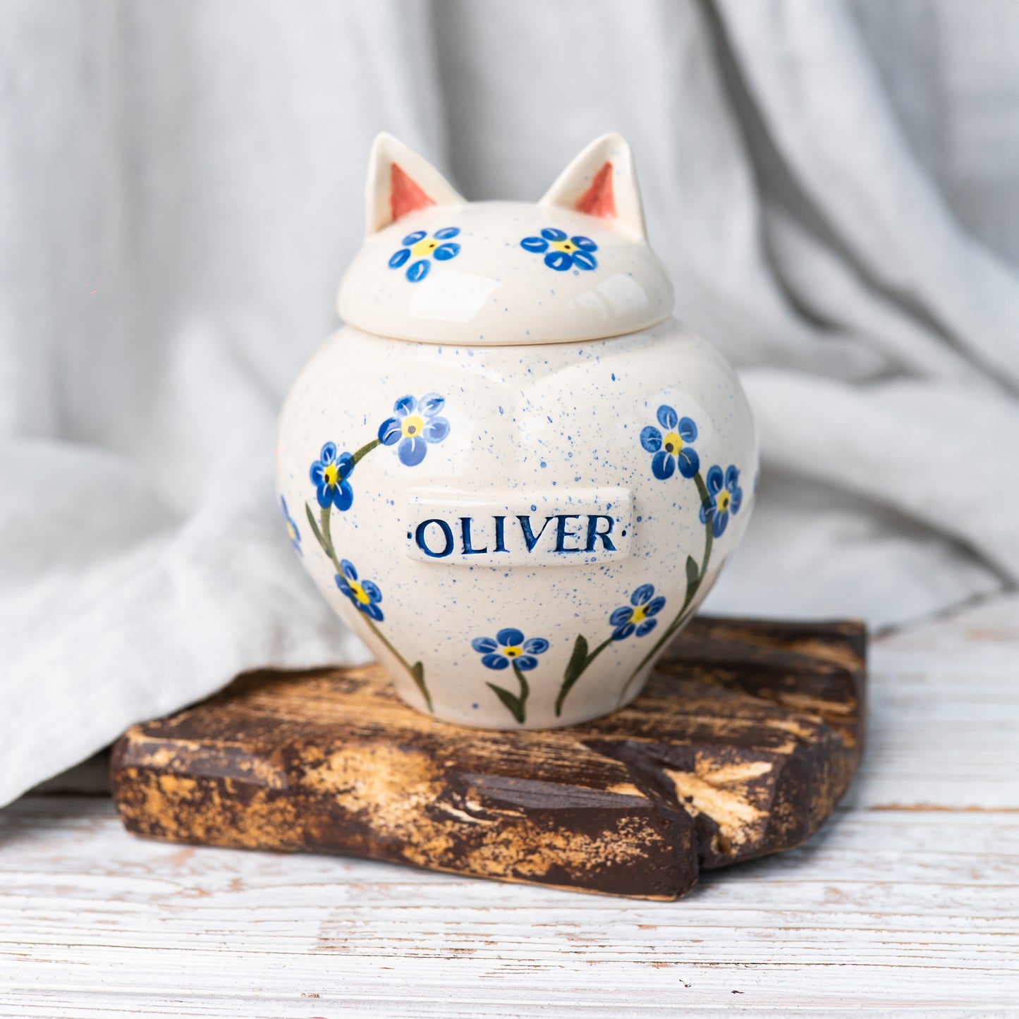 Hand-painted forget-me-not ceramic heart-shaped cat urn with sculpted ears on the lid by Mira Ceramics