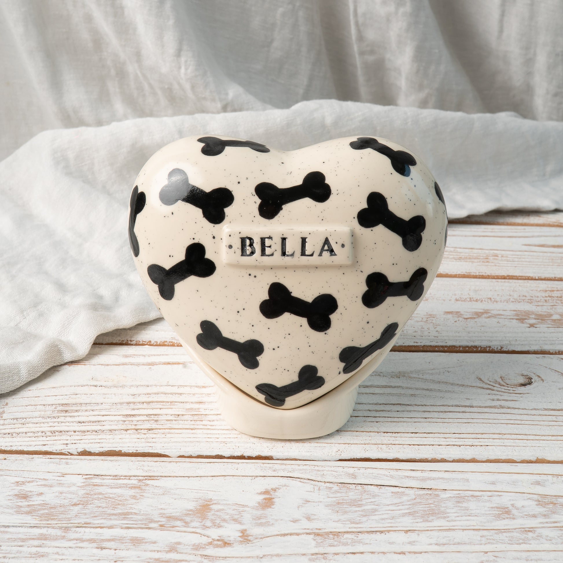 Custom heart-shaped ceramic dog urn with name and black bone pattern front view
