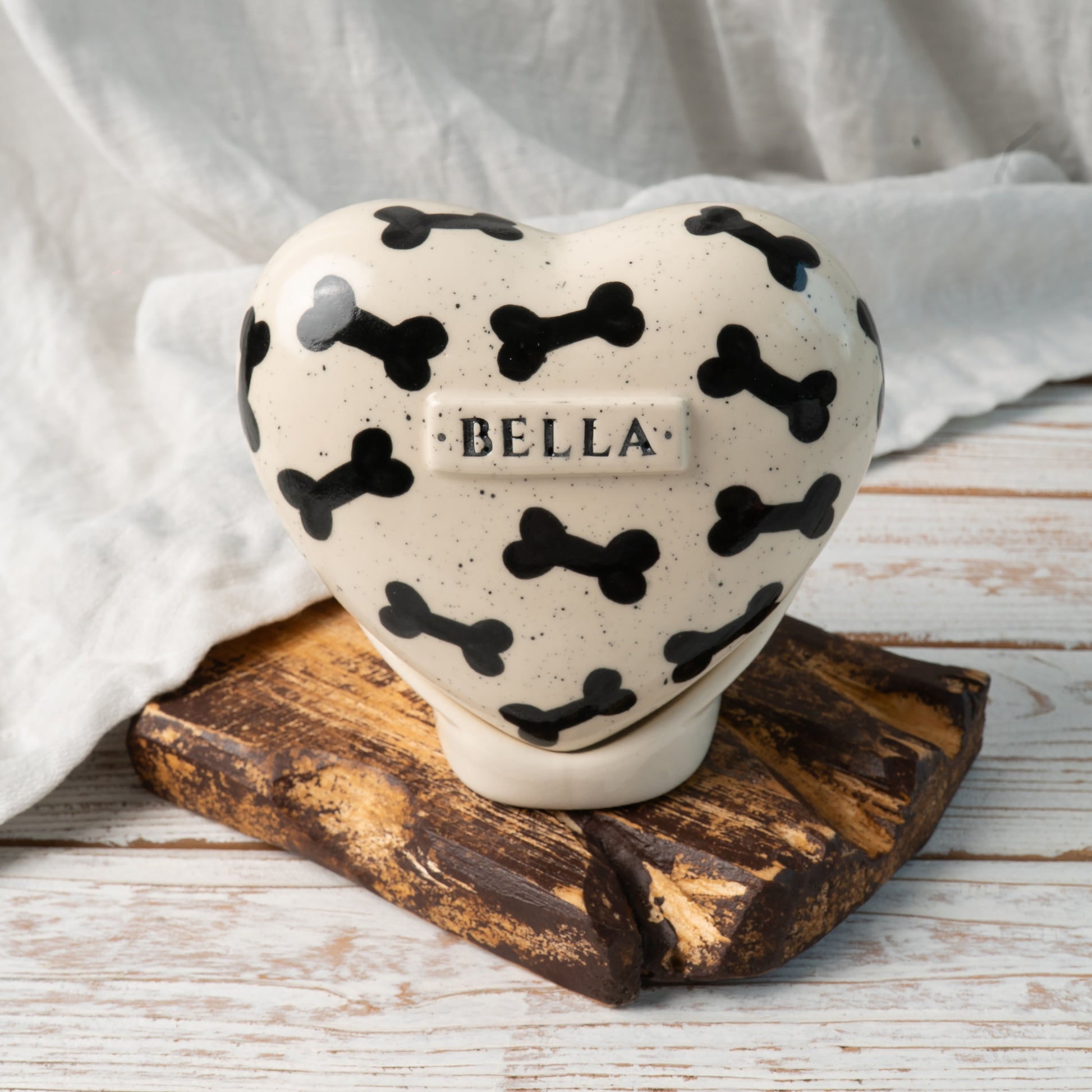Custom heart-shaped ceramic dog urn with name and black bone pattern front view