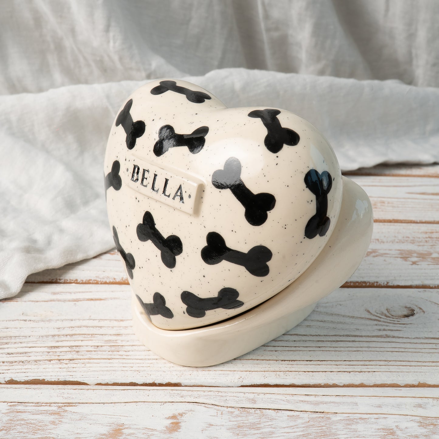 Side view of personalized dog memorial heart urn with stand featuring black bone artwork