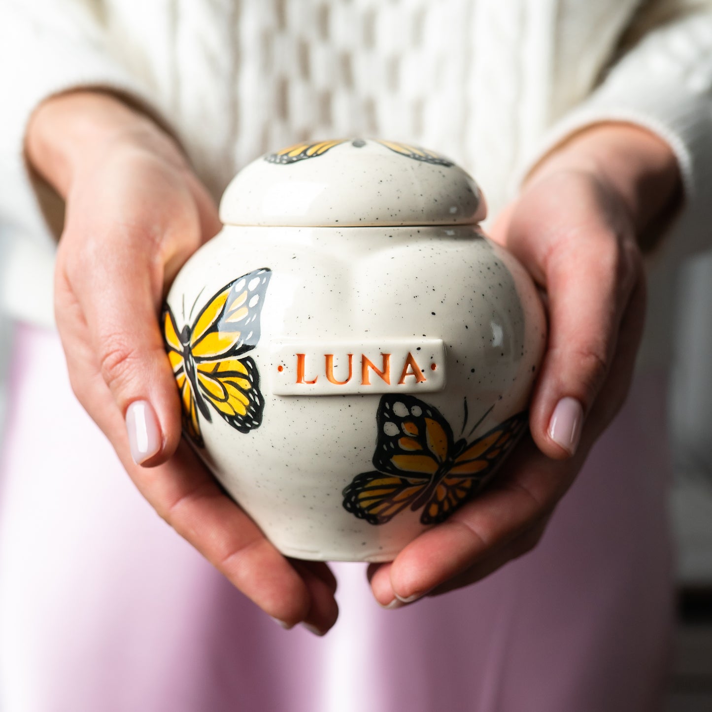 Holding a small Monarch butterfly heart keepsake urn for scale