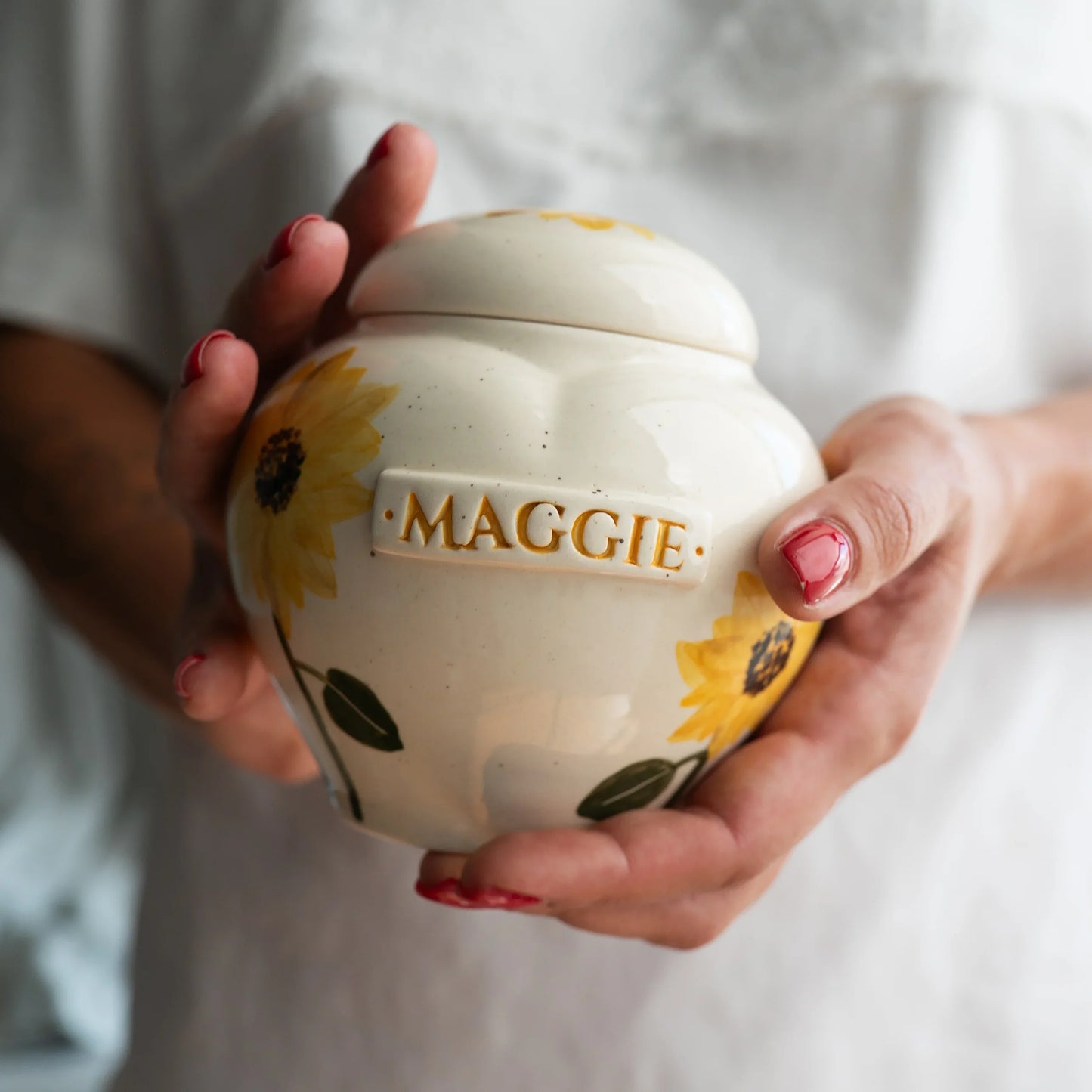 Holding a small sunflower heart keepsake urn for scale by Mira Ceramics.