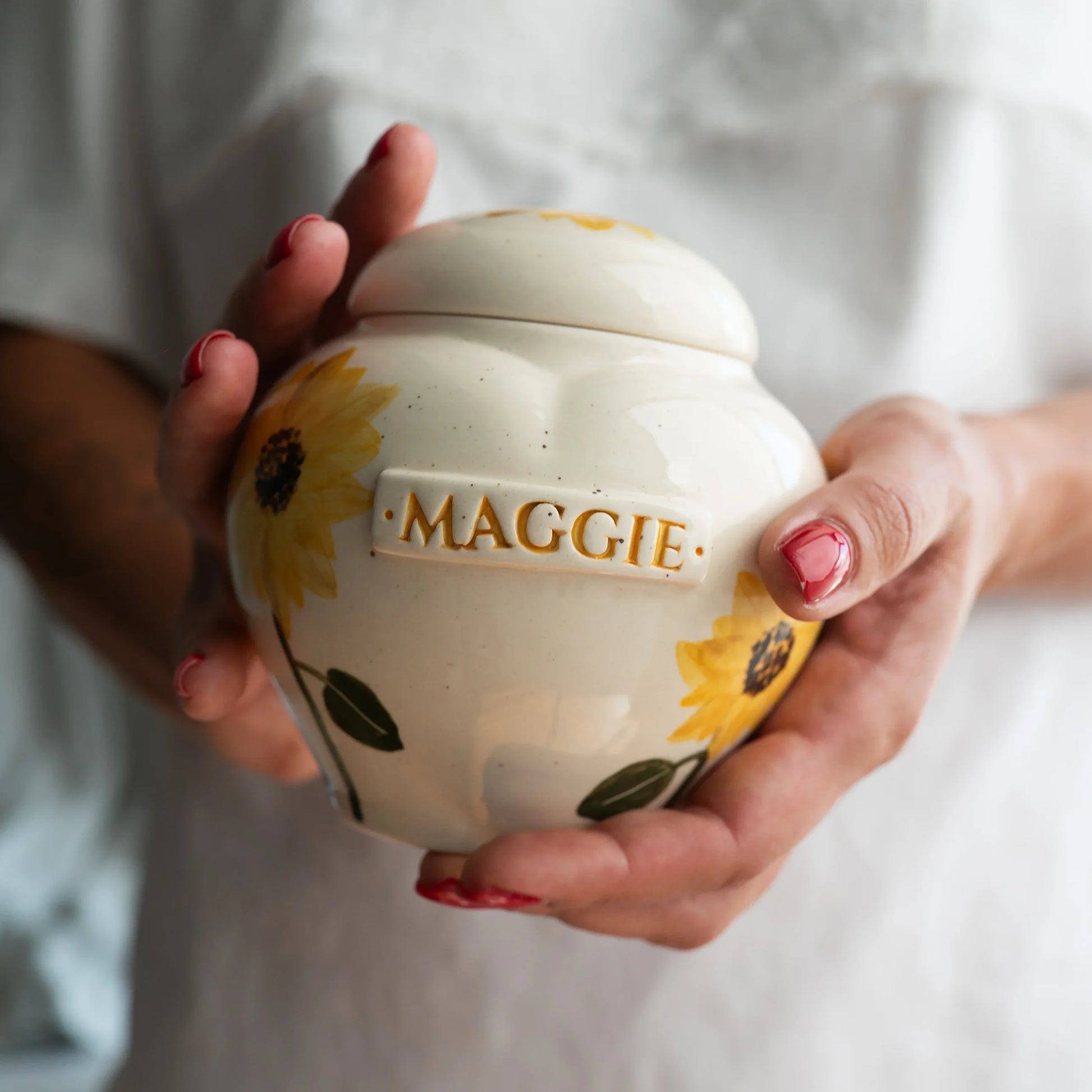Holding a small sunflower heart keepsake urn for scale by Mira Ceramics.