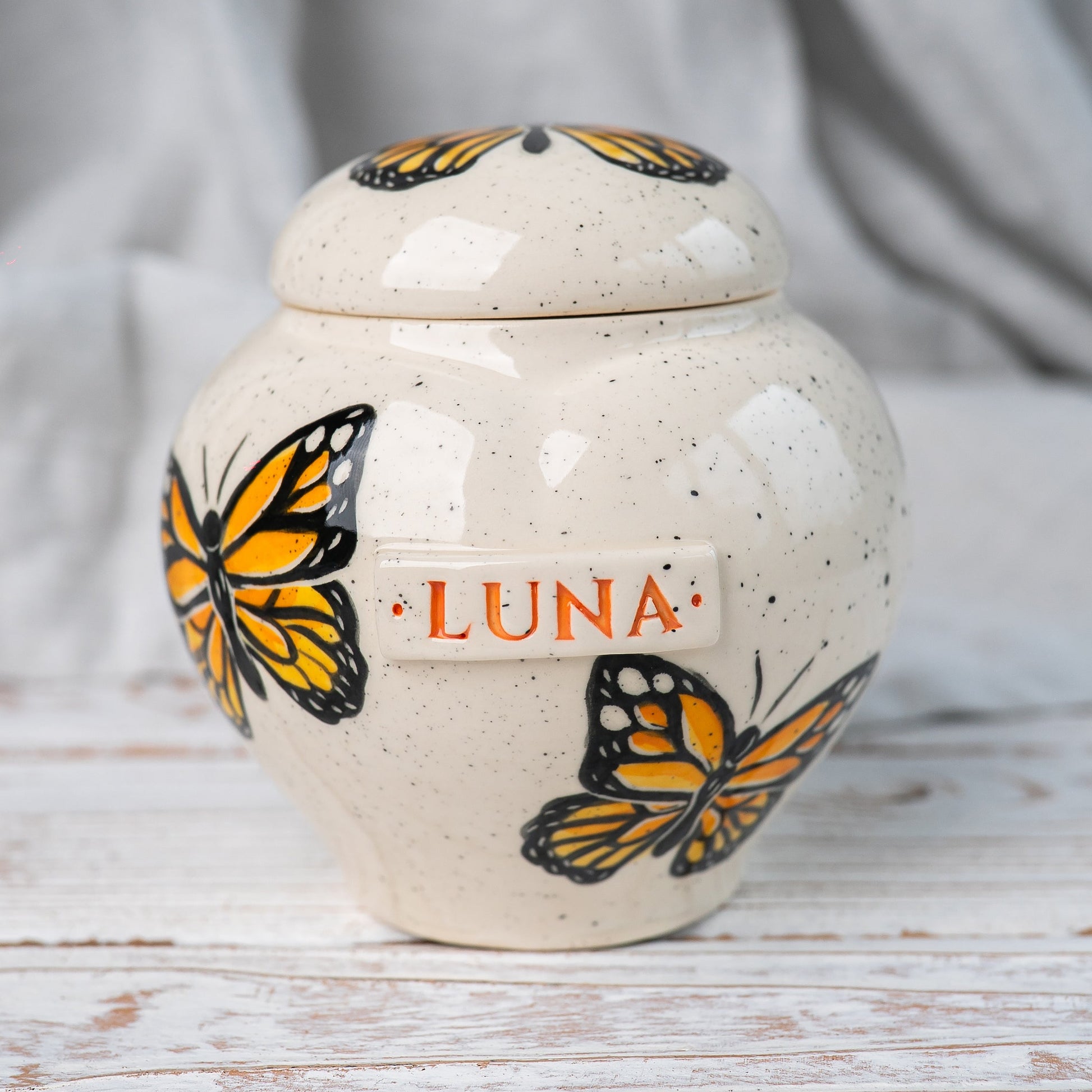 Hand-painted Monarch butterfly ceramic heart urn by Mira Ceramics.