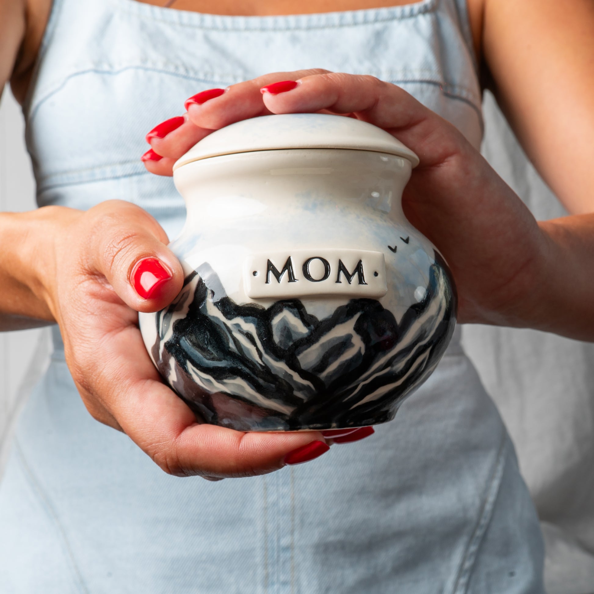 Small custom ceramic mountain keepsake urn held gently in hands for scale