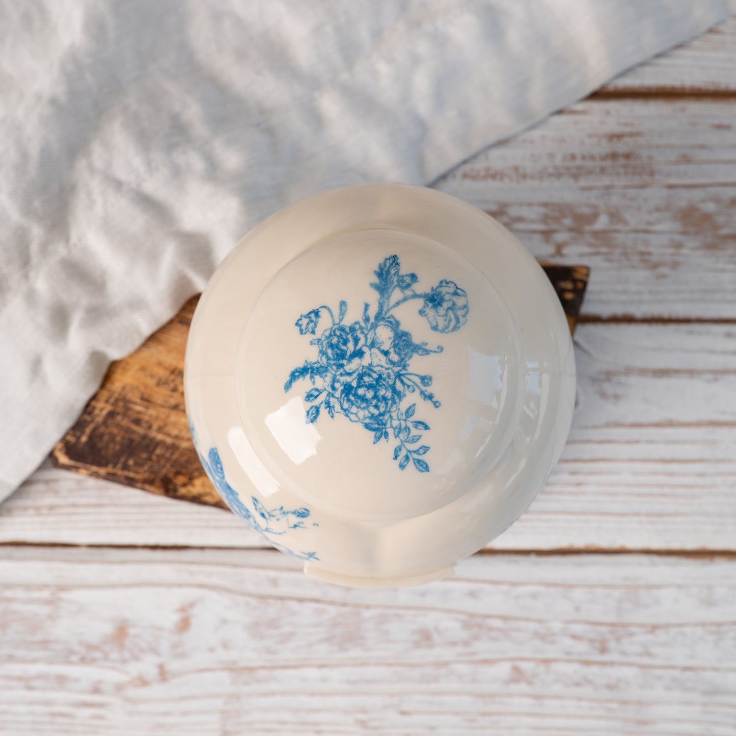 Top-down view of hand-painted ceramic lid with blue floral toile seamless pattern for small heart urn