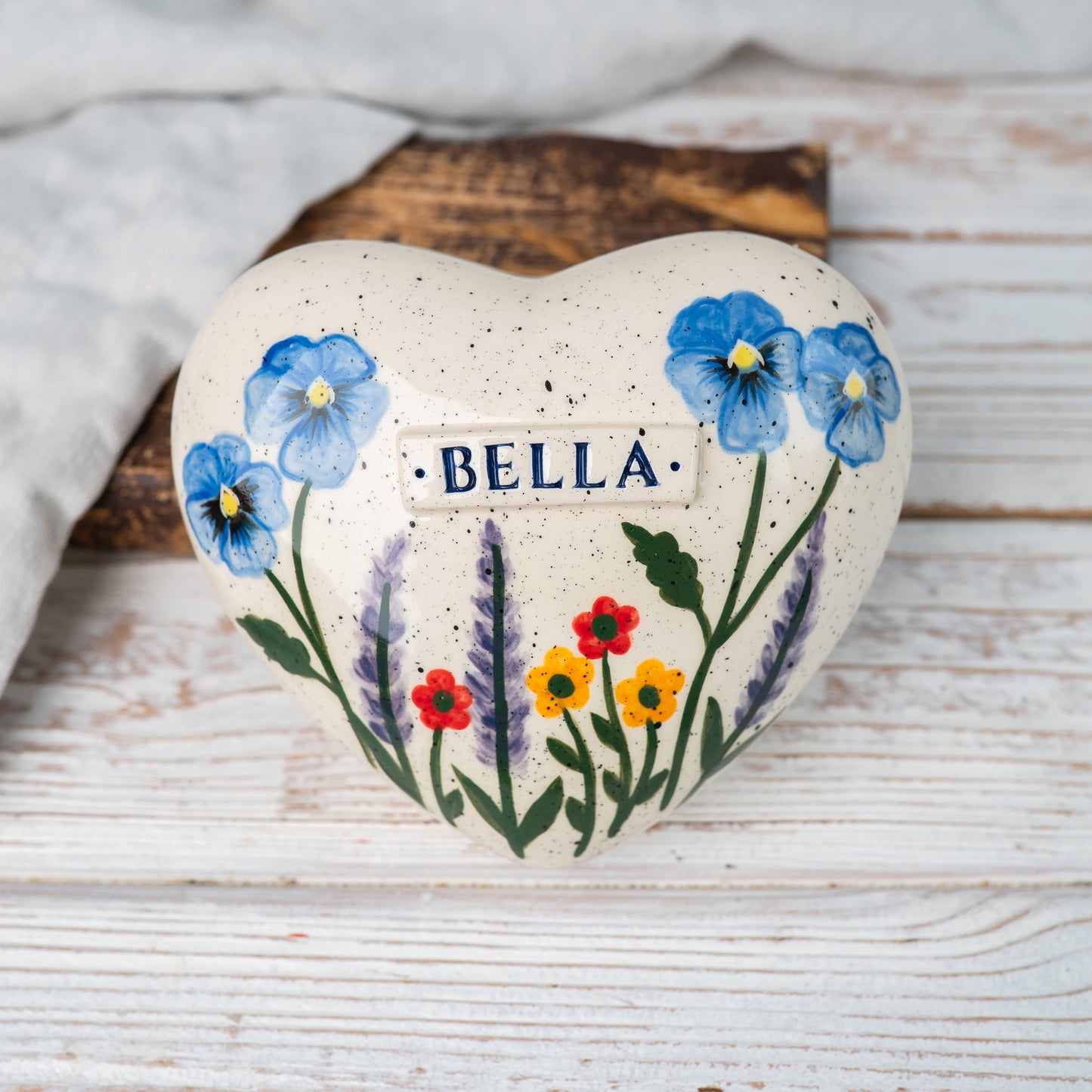 Top view of the ceramic heart urn showing the detailed hand-painted pansies, lavender, and red-yellow blossoms.