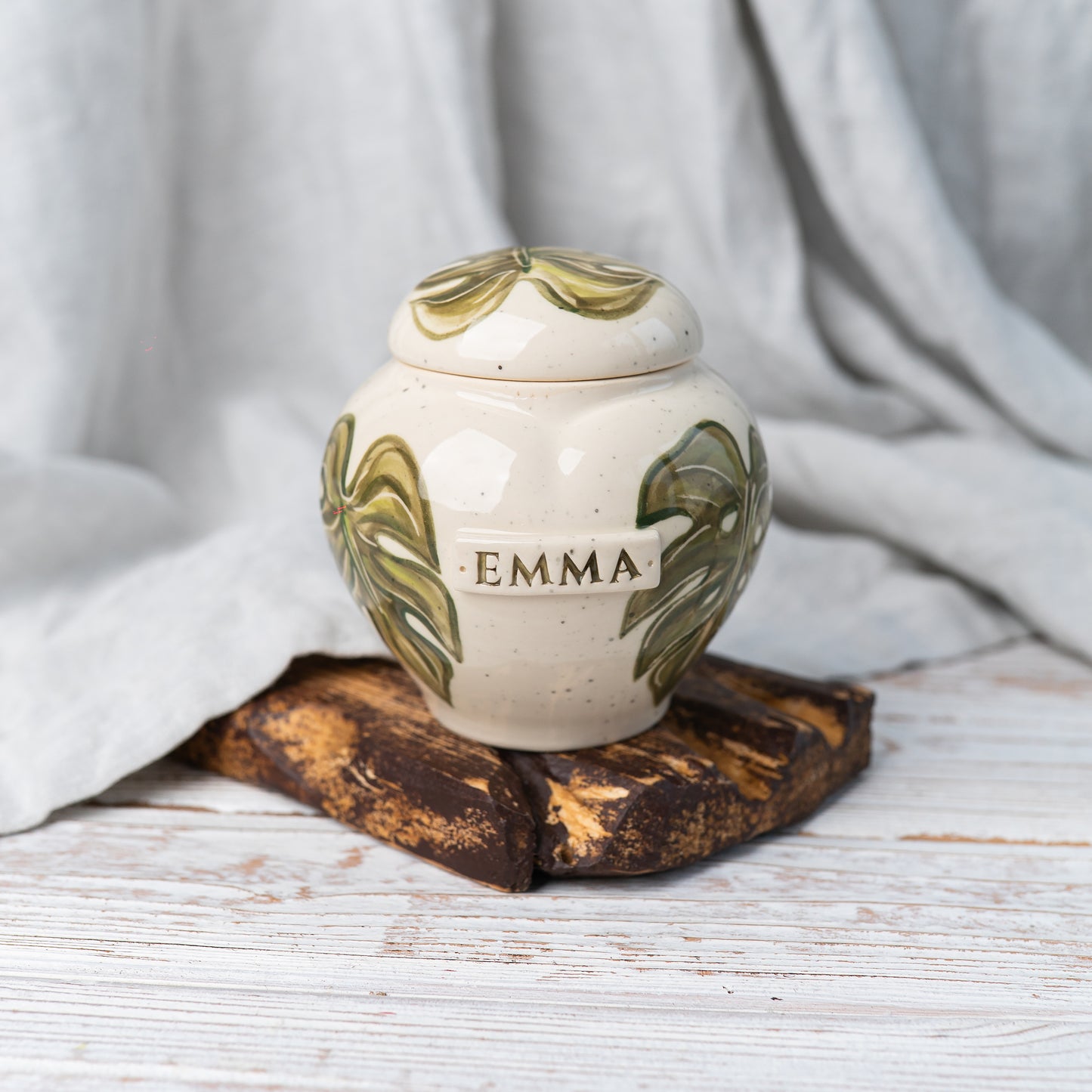 Front view of a white ceramic monstera keepsake for portion of human ashes