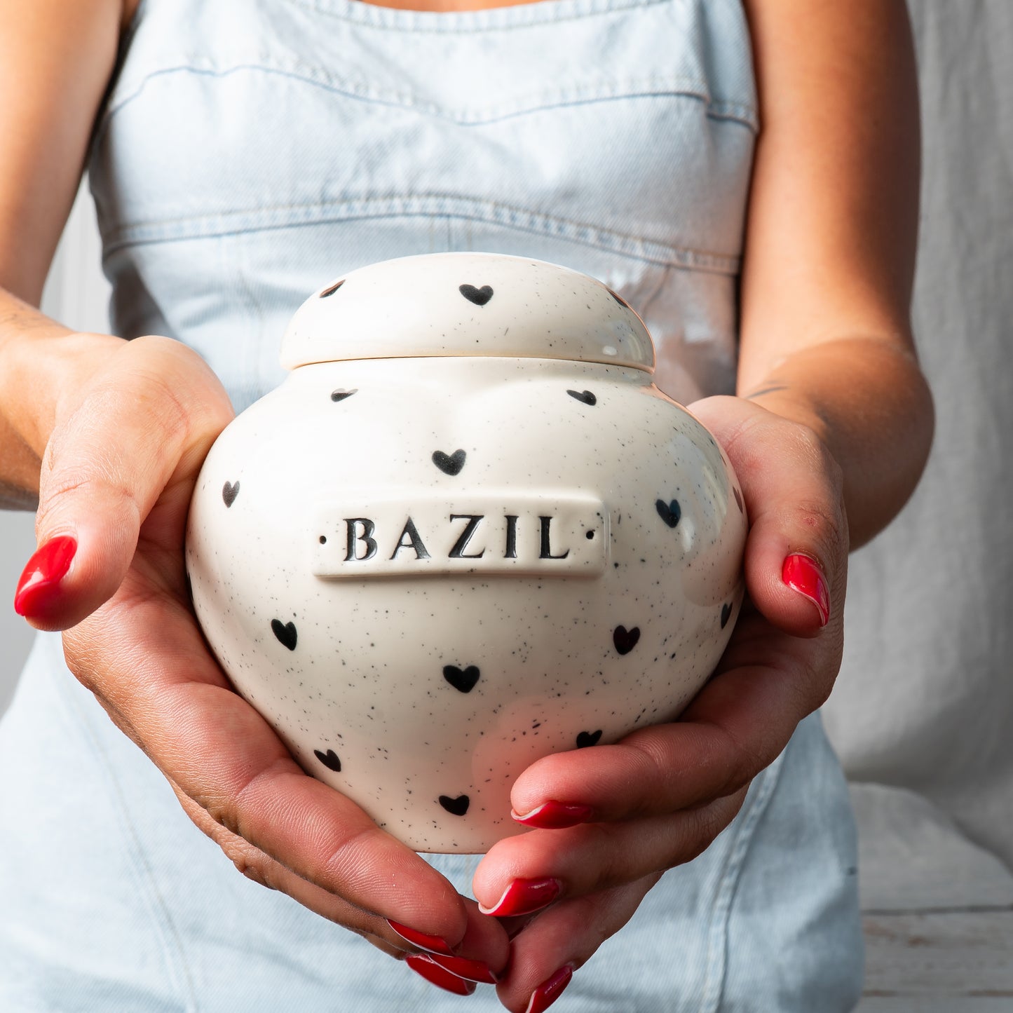 Small custom heart ceramic keepsake urn with heart print held gently in hands for scale