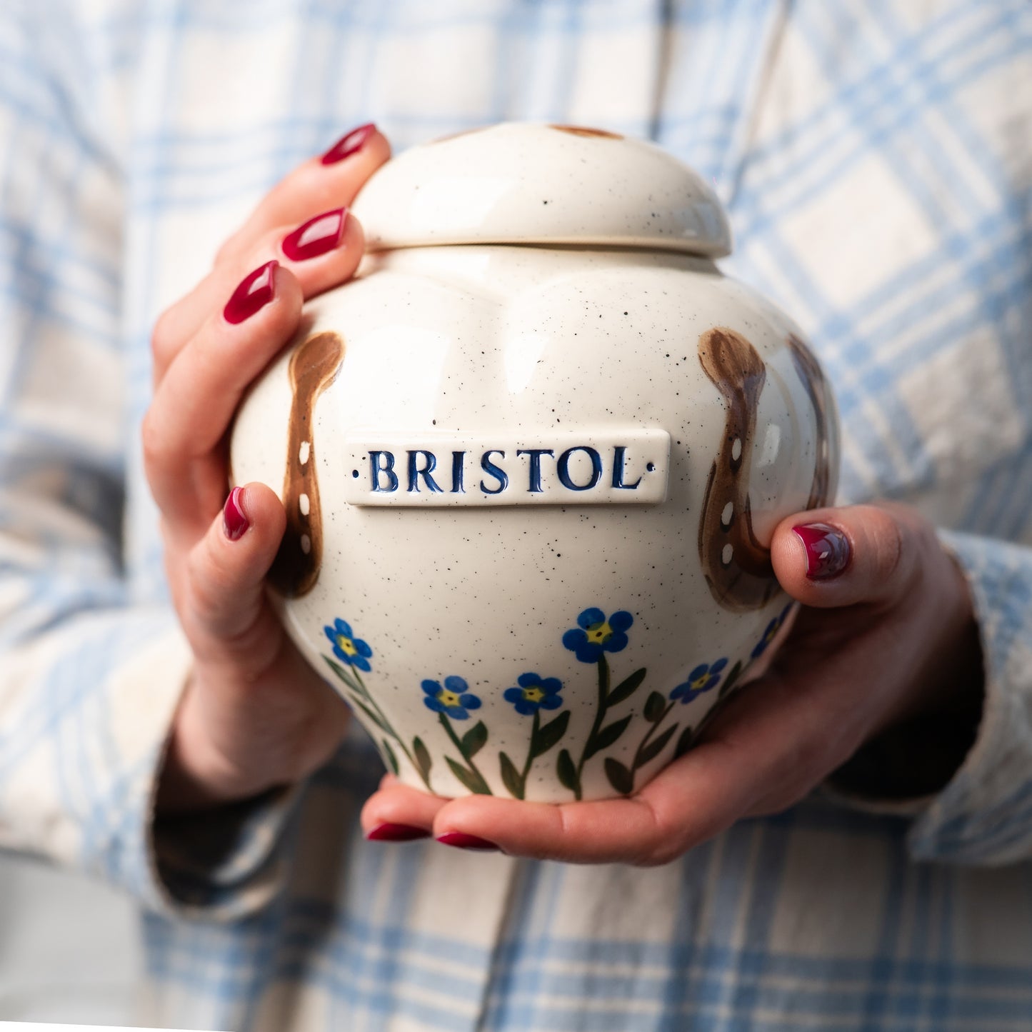 Holding a small handmade ceramic horse keepsake urn with forget-me-nots to show scale
