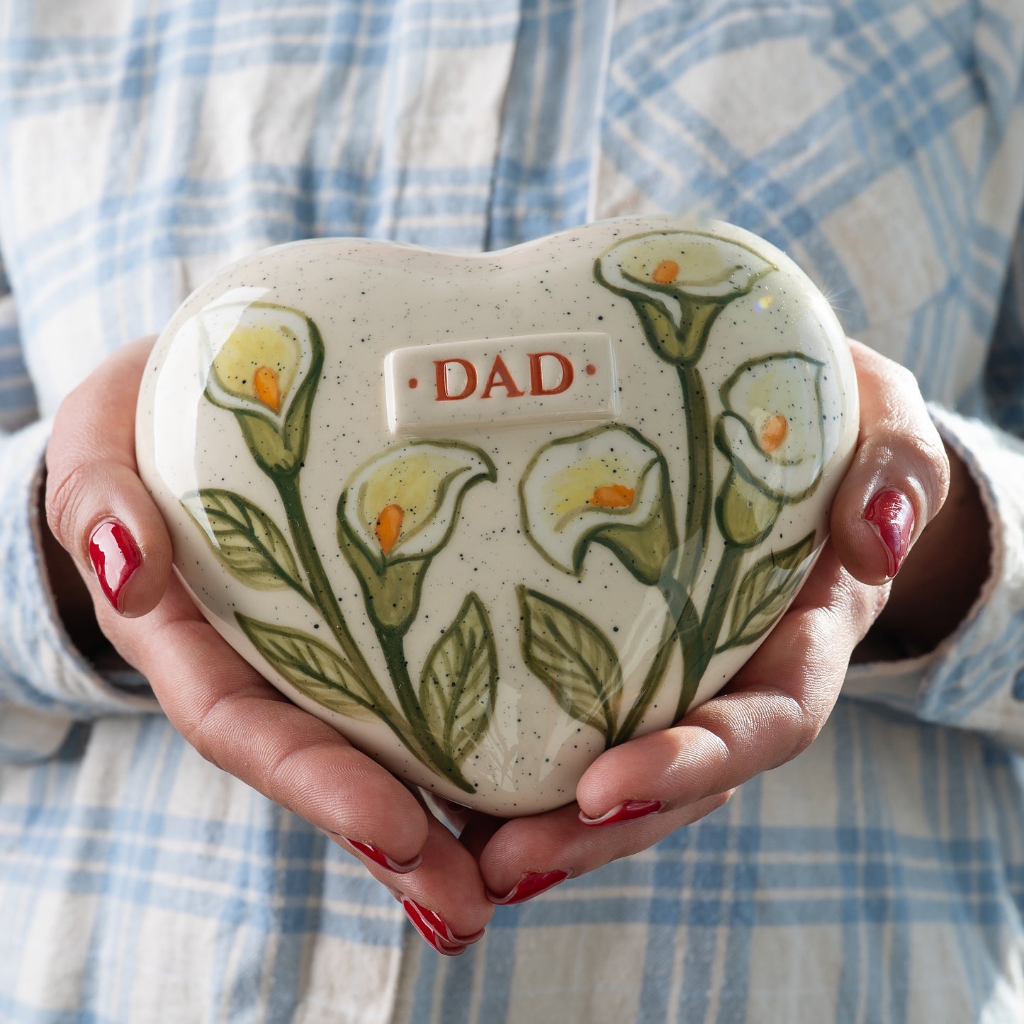 Small white calla lily keepsake urn held in hands to demonstrate the sharing size and delicate floral details for human or pet ashes.
