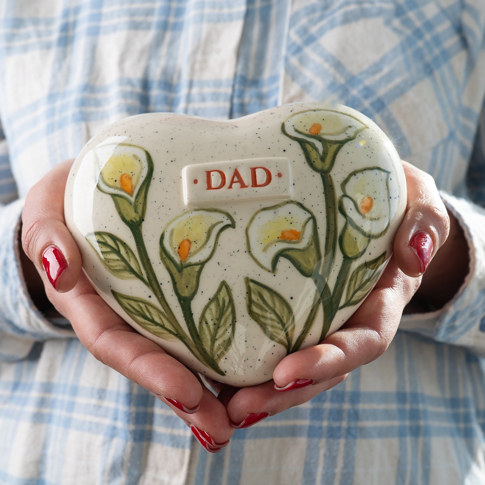 Small white calla lily keepsake urn held in hands to demonstrate the sharing size and delicate floral details for human or pet ashes.