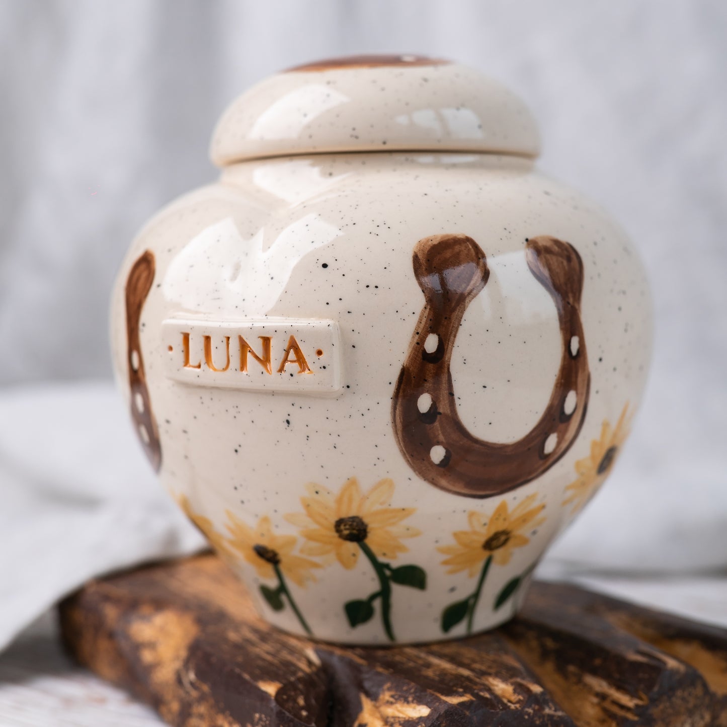 Side view of the ceramic urn showing a hand-painted lucky horseshoe detail