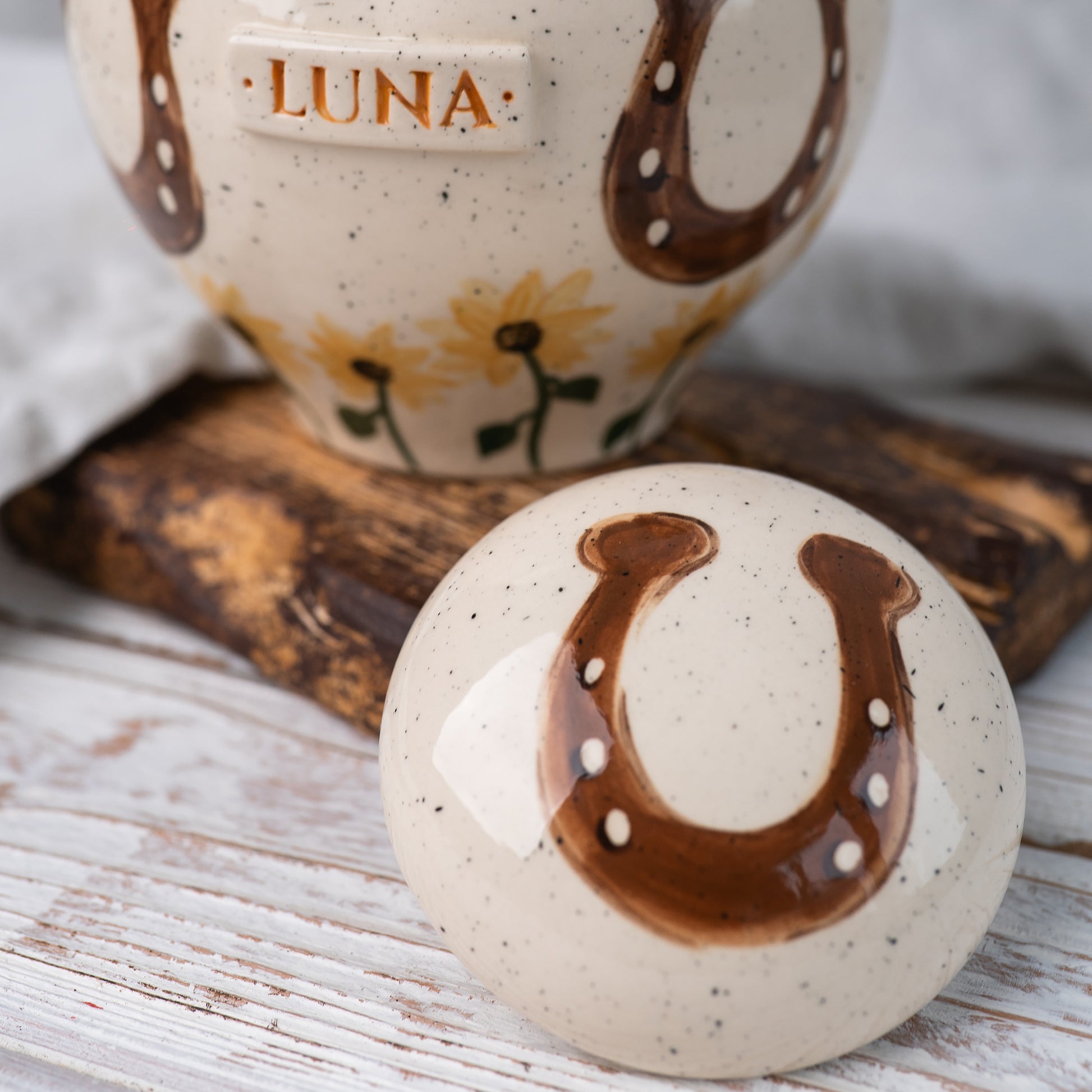 Close-up of the ceramic lid featuring a hand-painted horseshoe and sunflower motif