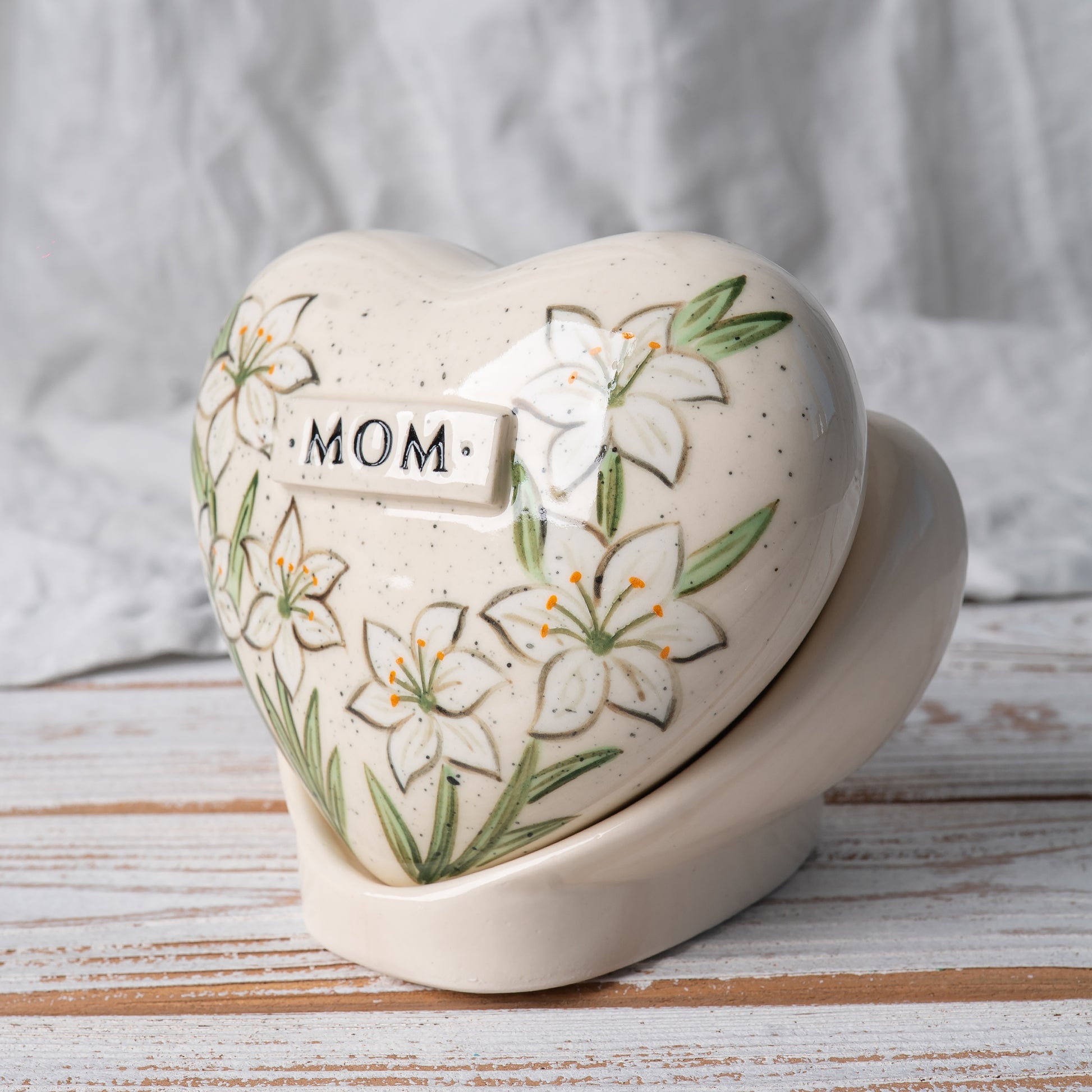 Side profile of the lily memorial urn on its stand, highlighting the smooth glaze and artisan pottery finish.