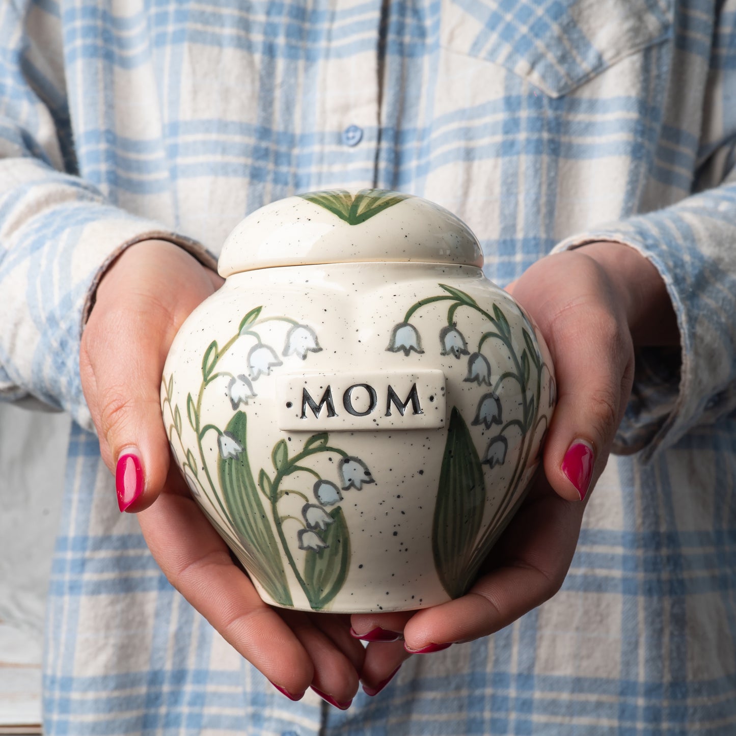 Small custom heart ceramic lily of the valley keepsake urn held gently in hands for scale