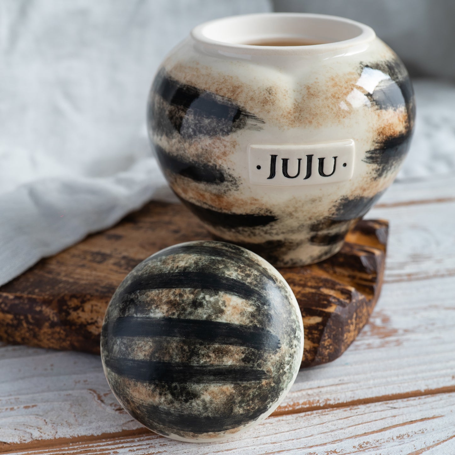 Close-up of hand-painted mackerel parallel stripes on a ceramic pet urn.