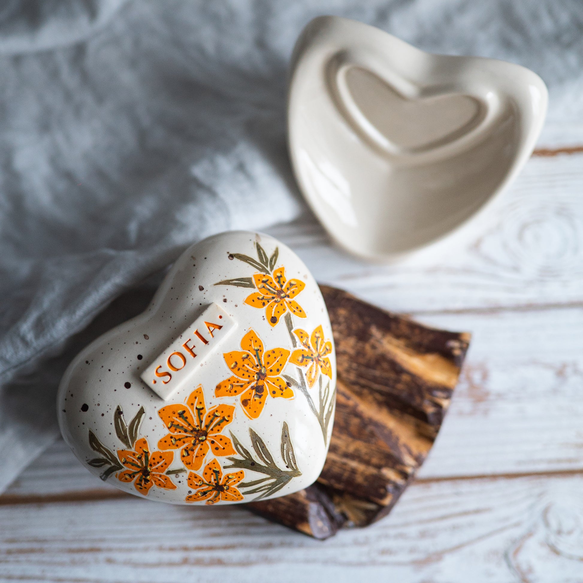 Top view of the heart-shaped ceramic urn, showing the detailed orange petals and green leaf accents.