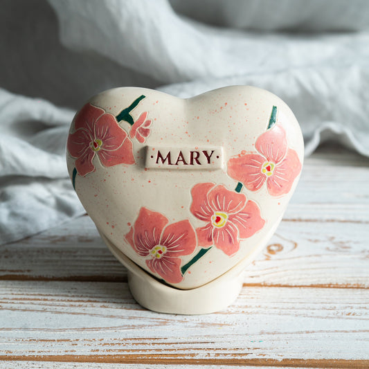 Hand-painted heart-shaped ceramic urn with elegant orchid flowers and a matching stand for human or pet ashes.