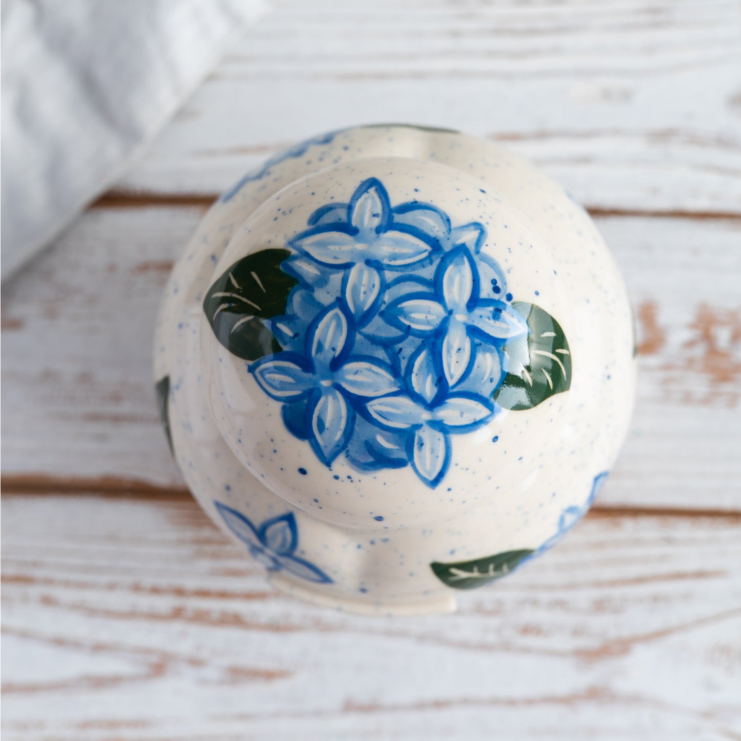 Overhead view of hand-painted hydrangea petals on ceramic urn lid