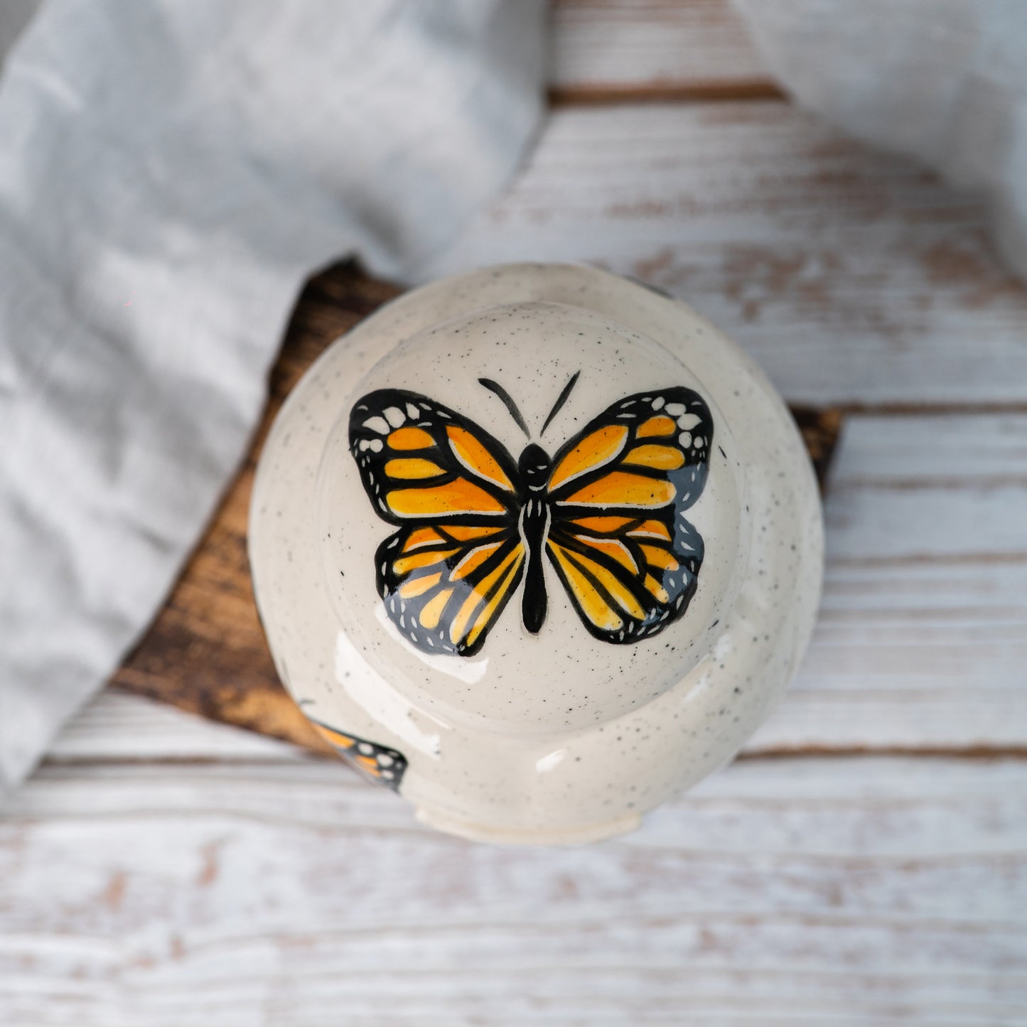 Overhead view of Monarch butterfly pattern on ceramic urn lid by Mira Ceramics.