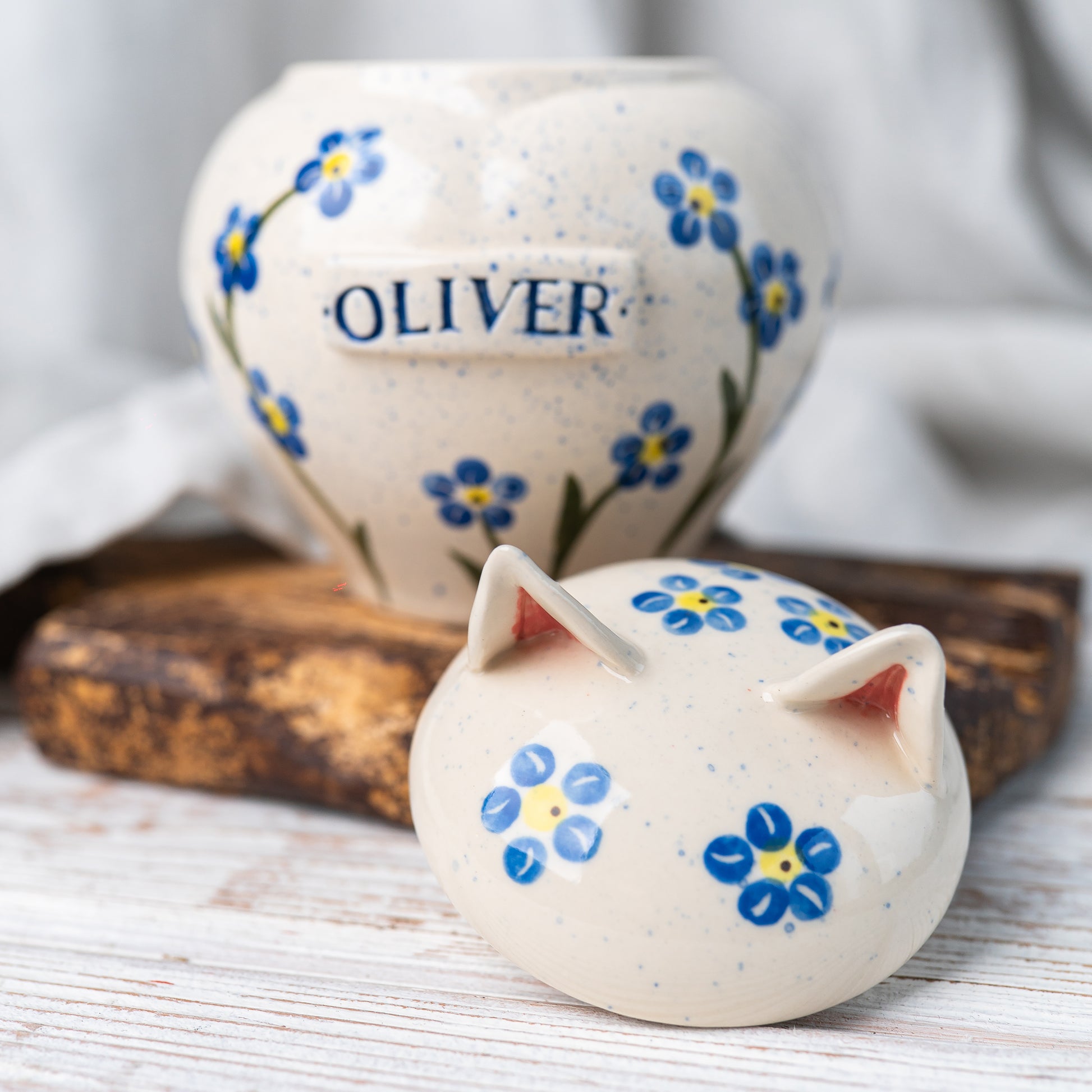Open Mira Ceramics cat urn with the forget-me-not patterned lid featuring sculpted ears resting beside it.
