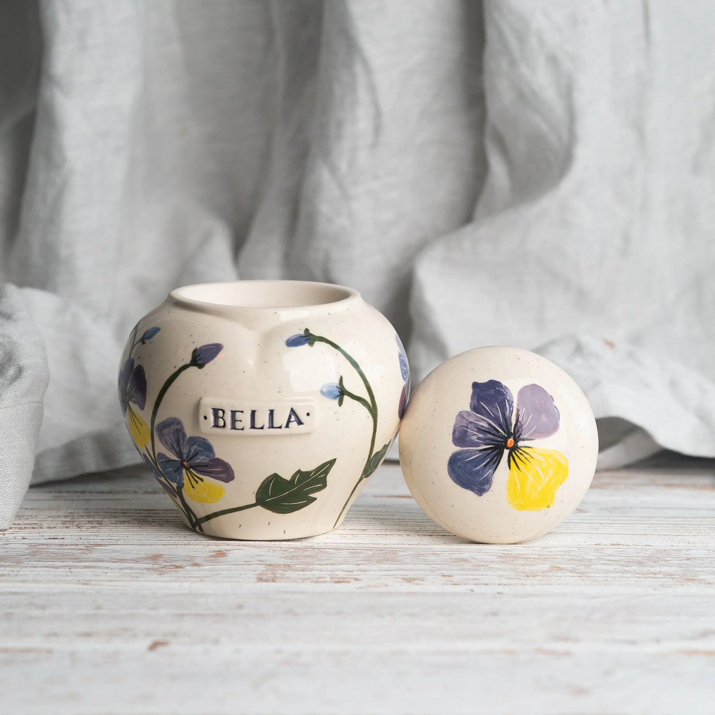 Front view of hand-painted pansies on ceramic urn and on lid