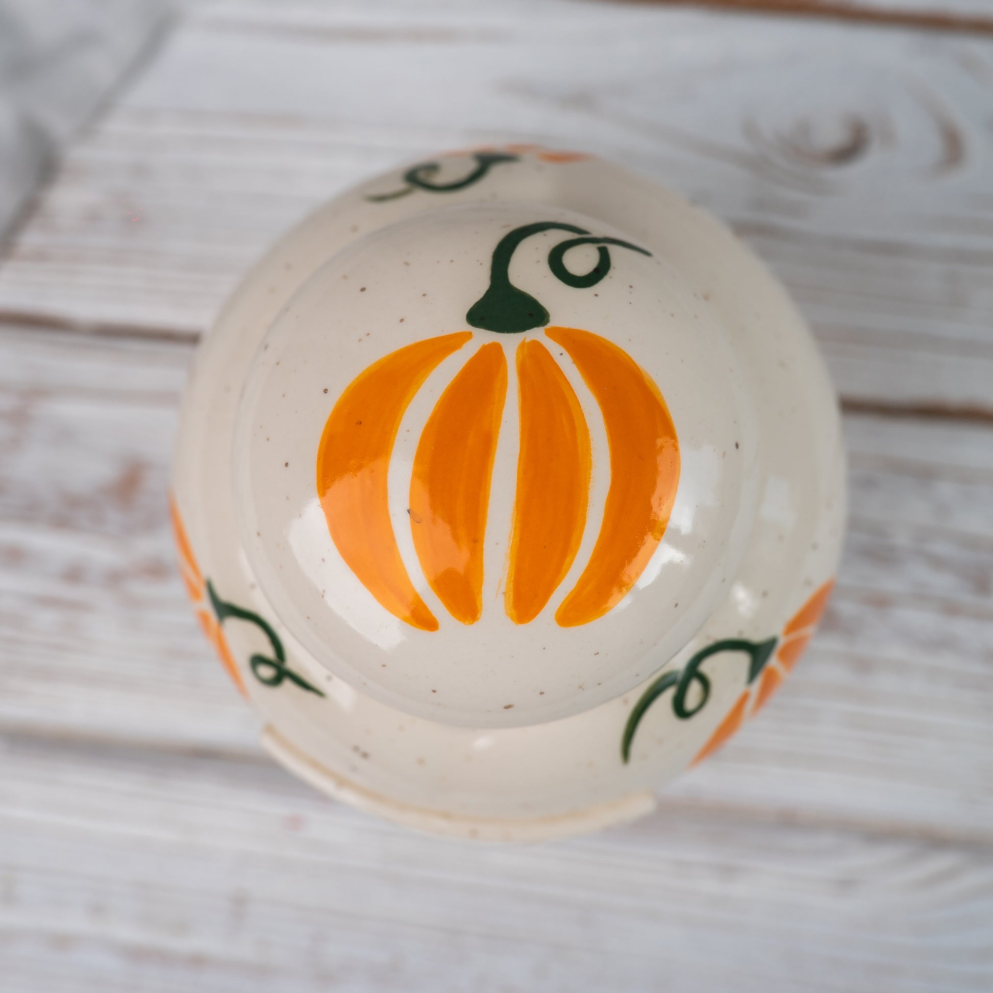 Overhead view of the closed heart-shaped ginger cat urn showing the hand-painted pumpkin pattern