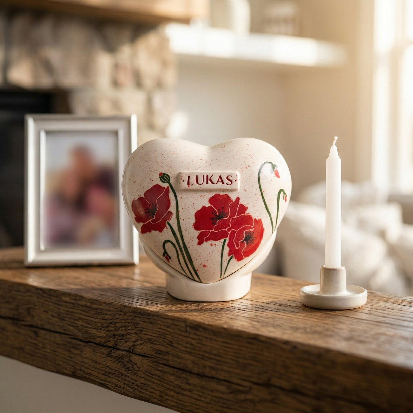 A dignified home memorial display with a red poppy flower heart urn on a wooden shelf next to a small candle.
