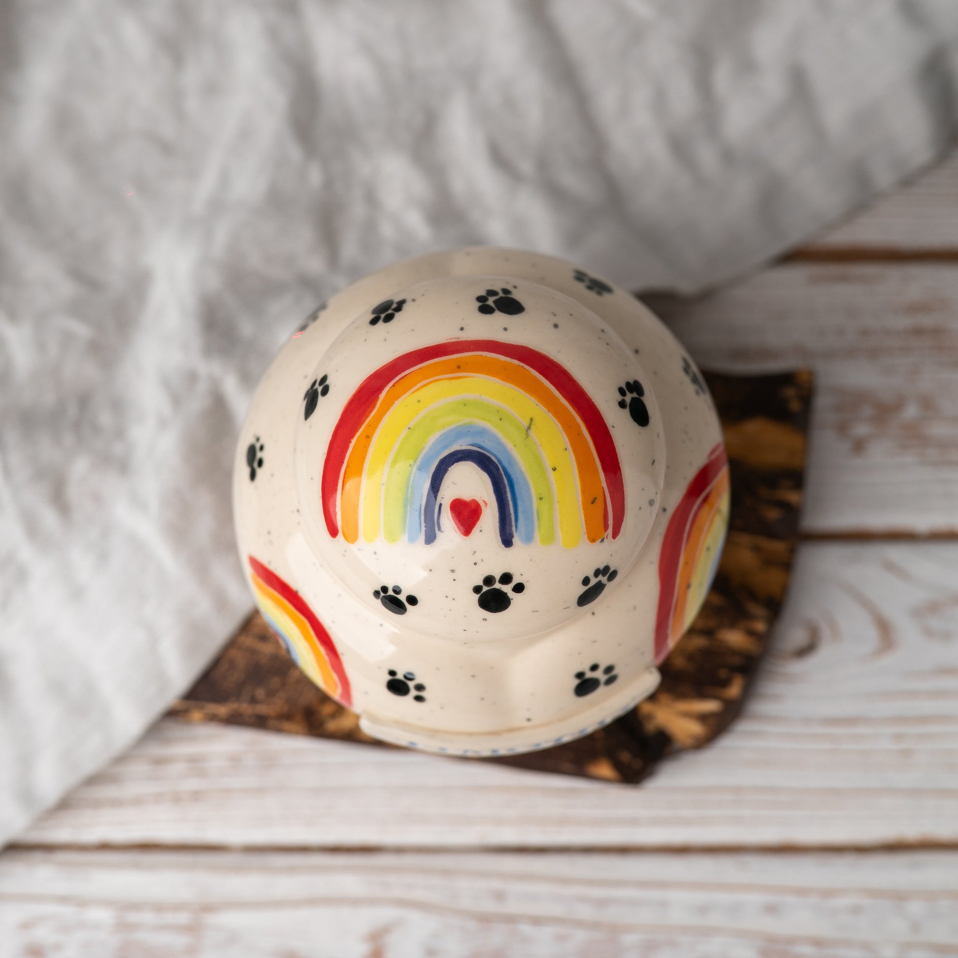 Top view of the heart-shaped pet memorial pot urn showing the hand-painted rainbow and ceramic lid.