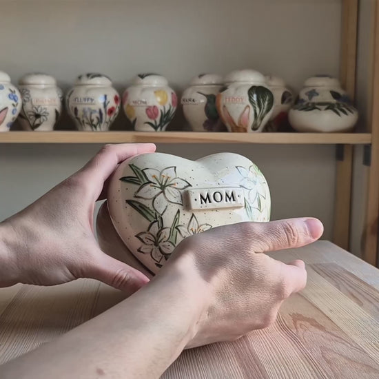 Video showcase of a hand-painted white lily heart-shaped ceramic urn on a stand