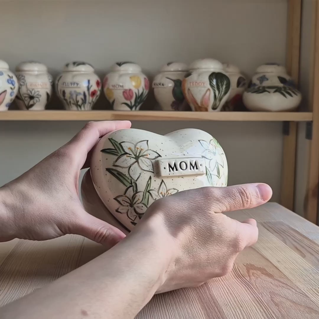 Video showcase of a hand-painted white lily heart-shaped ceramic urn on a stand