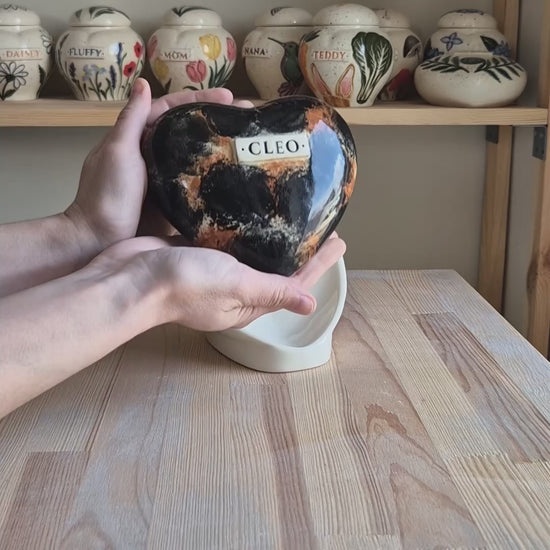 Video showcase of a hand-painted tortoiseshell cat heart-shaped ceramic urn on a stand