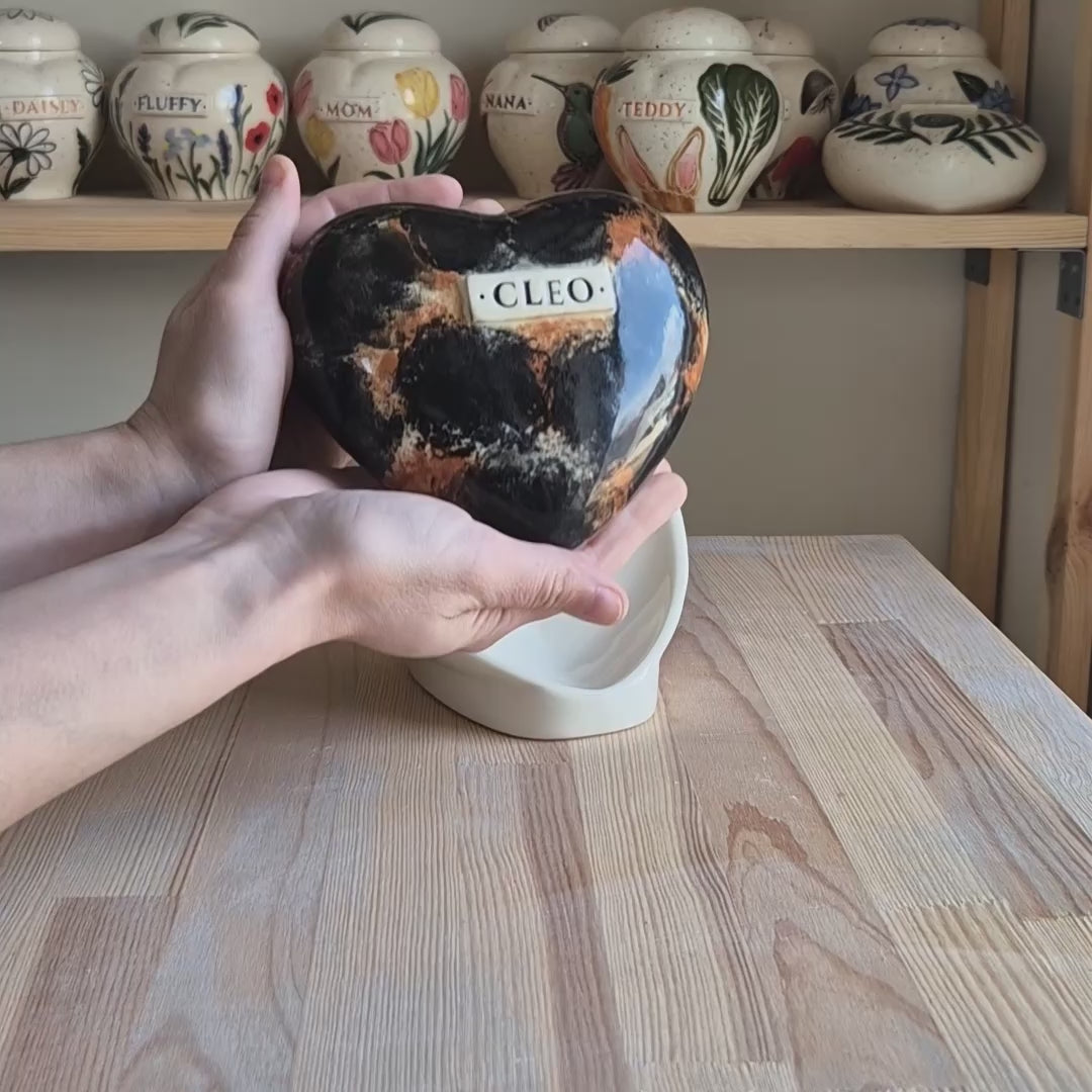 Video showcase of a hand-painted tortoiseshell cat heart-shaped ceramic urn on a stand