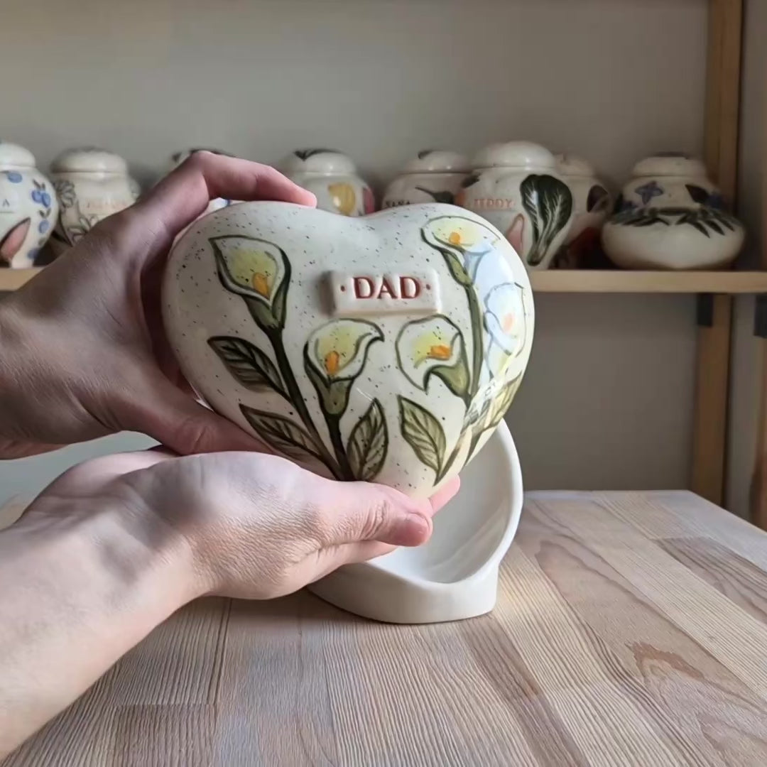 Video showcase of a hand-painted calla lily heart-shaped ceramic urn on a stand