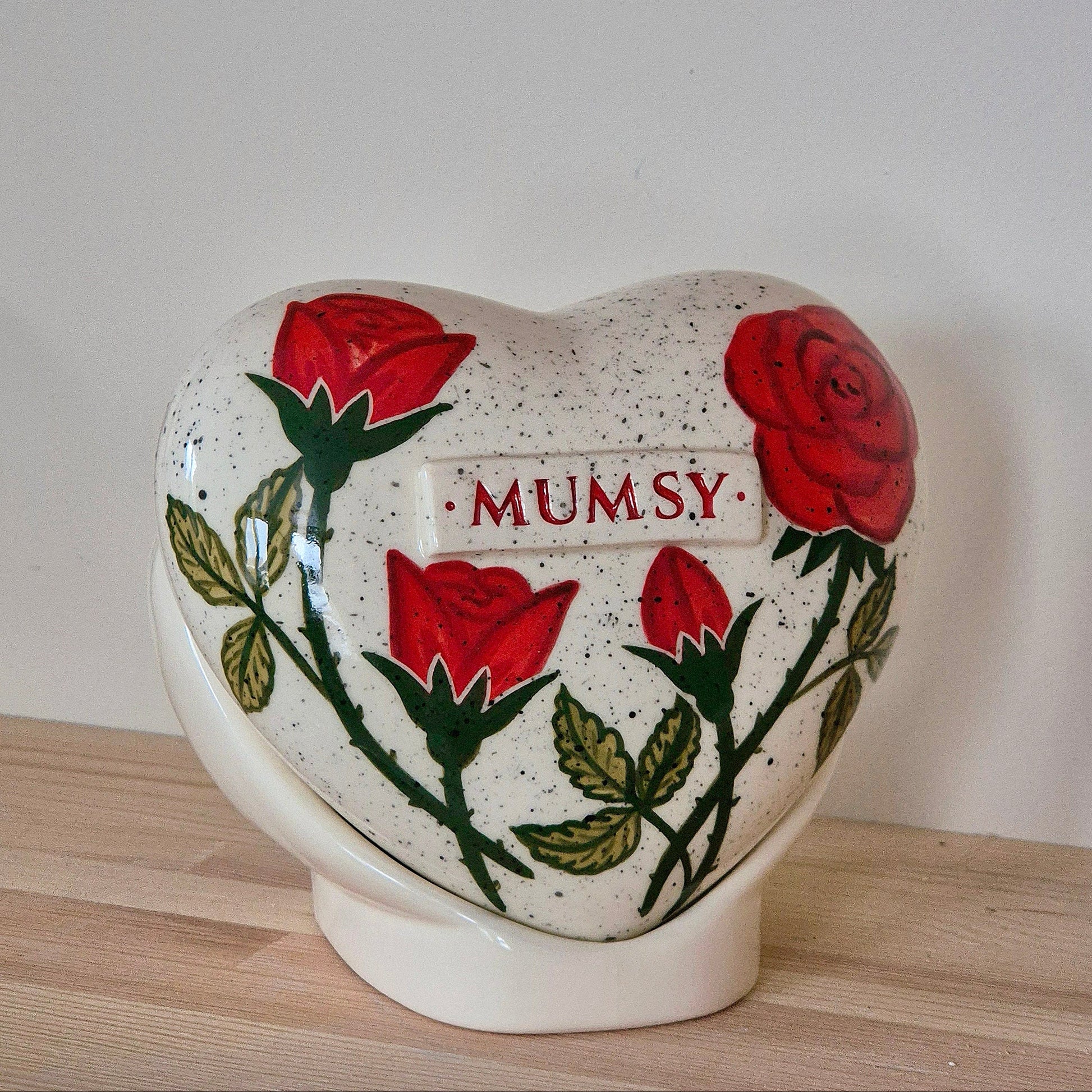 Hand-painted heart-shaped ceramic urn with a red rose and matching stand for human or pet ashes.
